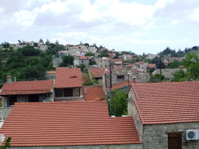 Het wijndorp Lofou op een groene helling achter Limassol, met stenen huizen en rode pannendaken