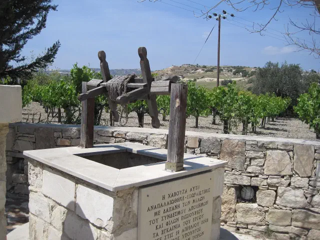 De gerestaureerde dorpsput in het oude dorp van Pissouri met een wijngaard erachter